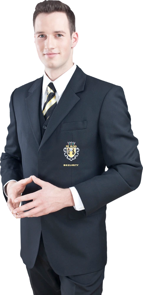 Mann in einem schwarzen Anzug mit gestreifter Krawatte und Sicherheitsabzeichen steht mit verschränkten Händen.